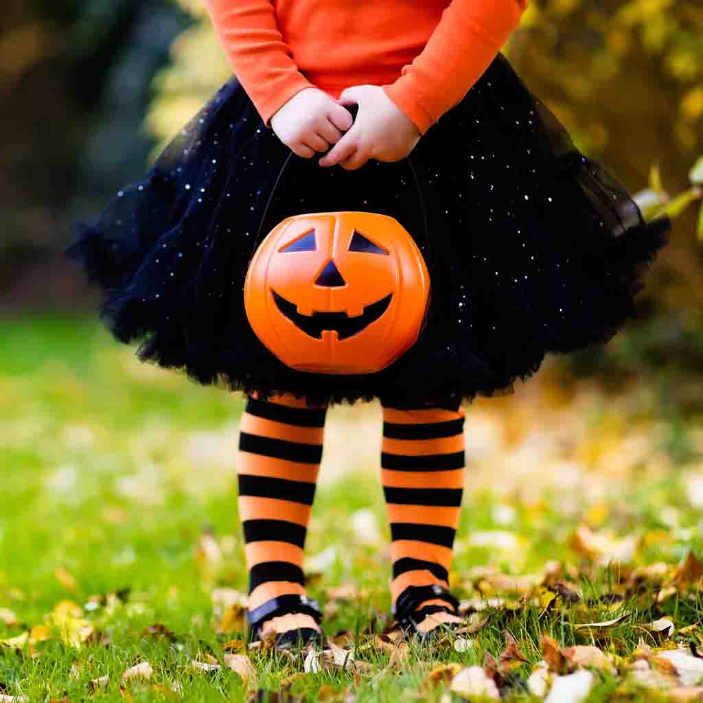 little girl in witch costume holding halloween bucket